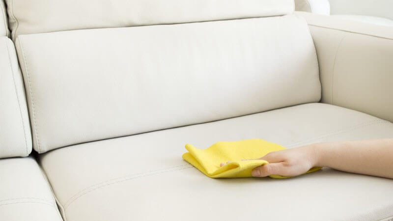 تمیز کردن سطح مبل با استفاده از یک دستمال توسط یک فرد